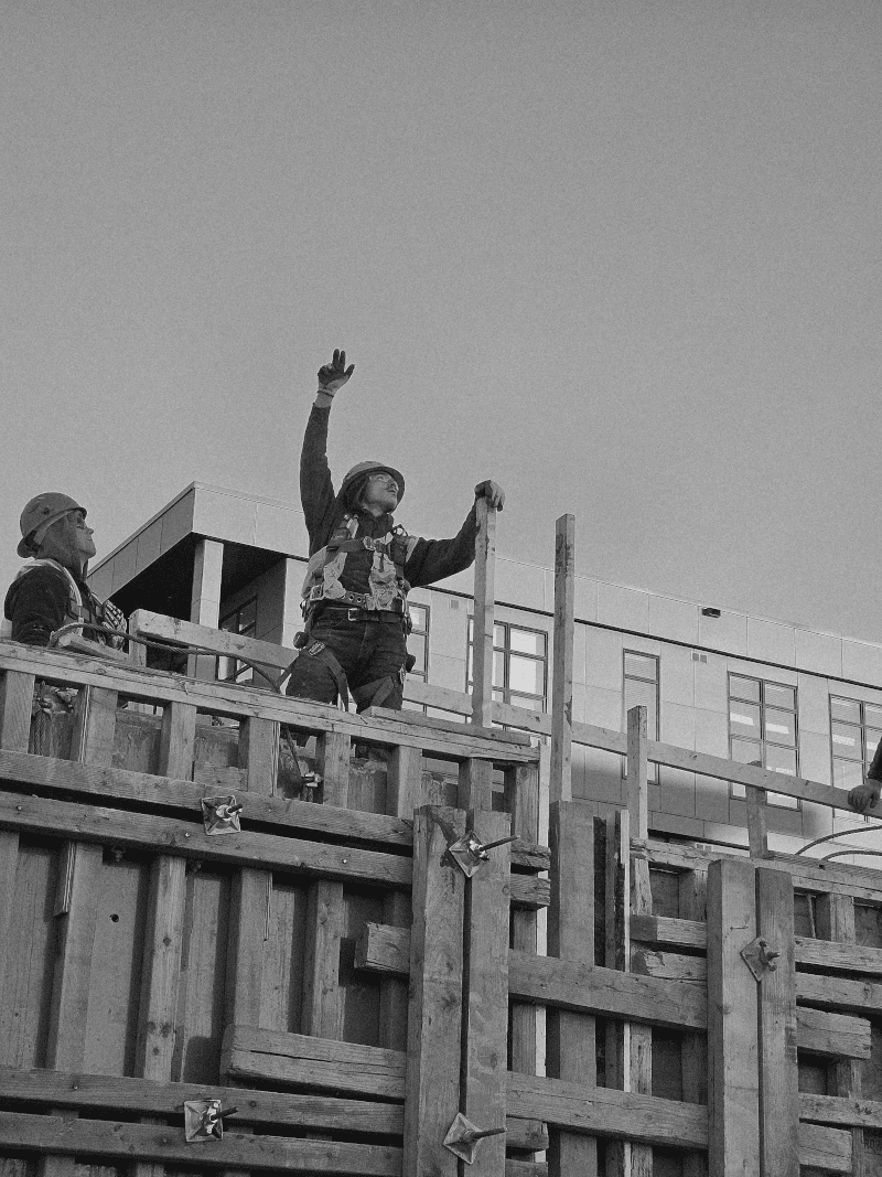 Construction workers installing wooden formwork system at building site