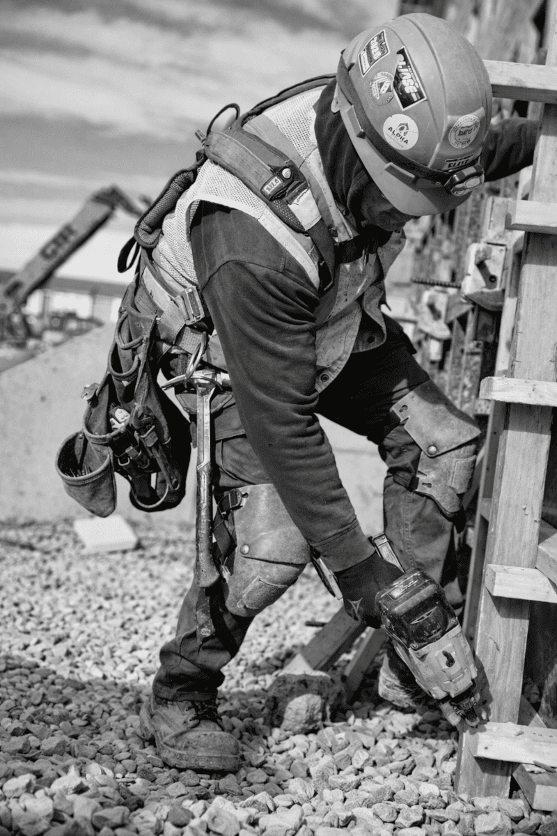 Construction worker drilling formwork structure at active construction site