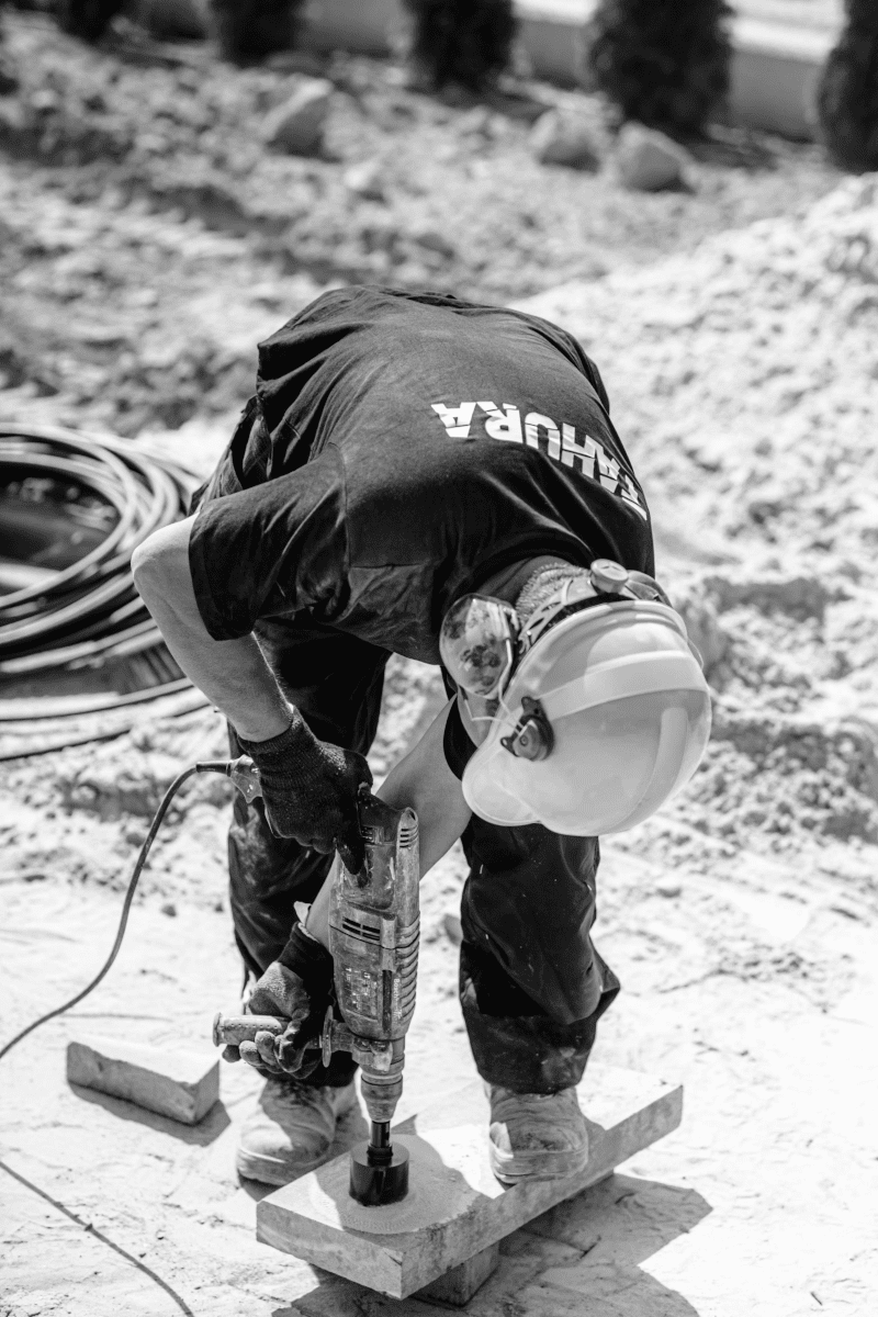 Construction worker drilling into concrete foundation at active job site
