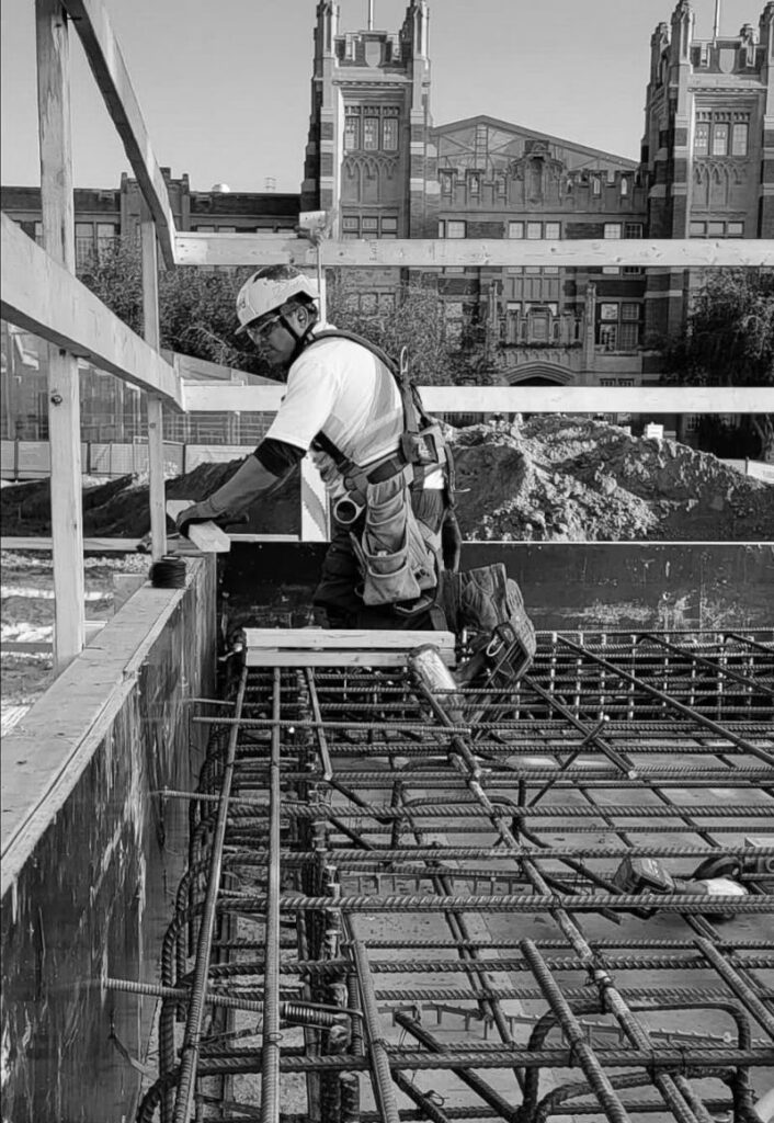 Construction workers installing formwork and reinforcement on elevated concrete slab at job site